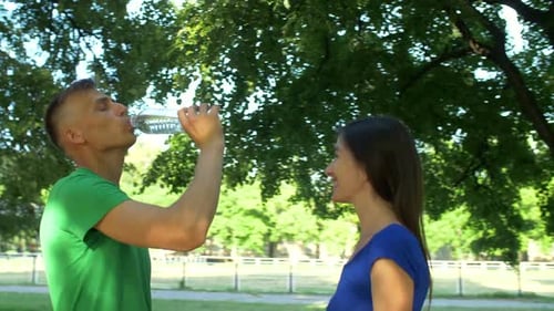 Playful Couple Sharing Water in the Park