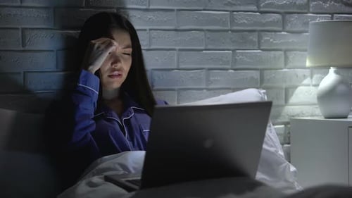 Woman Using Laptop in Bed at Night