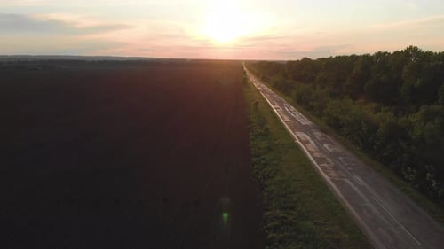Gerade nasse einsame Straße bei Sonnenuntergang nach Regen. Perspektivischer Blick auf die Straße.