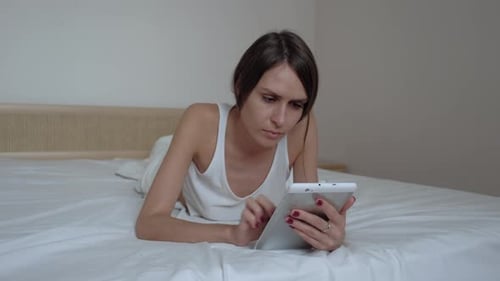 Woman Using Tablet While Lying on Bed