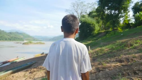 Menino asiático andando perto do rio