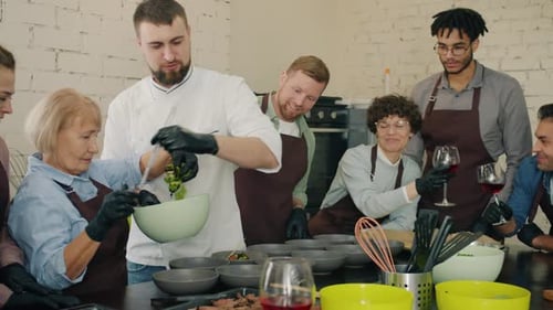 Multiethnische Gruppe von Menschen, die Mahlzeiten unter Anleitung eines männlichen Küchenchefs kochen und servieren