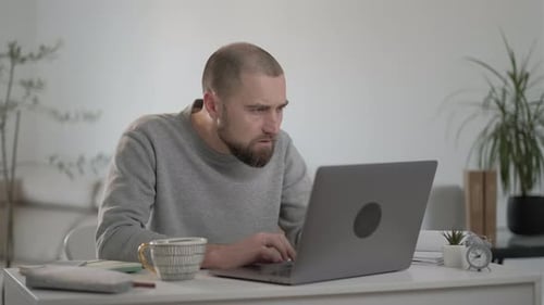 Man Working on Laptop at Desk at Home