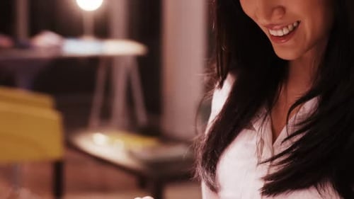Woman Smiles While Using Tablet in Warmly Lit Room