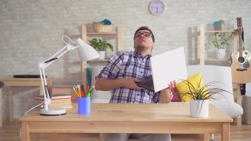 Leaking From the Ceiling To a Worried Young Man with a Laptop Sitting at a Table