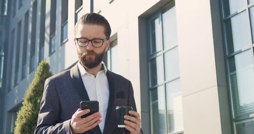 businessman in formal suit has phone call during coffee time near big city building