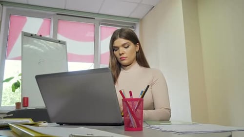 Tired Female Student Rubbing Temples Working on a Laptop