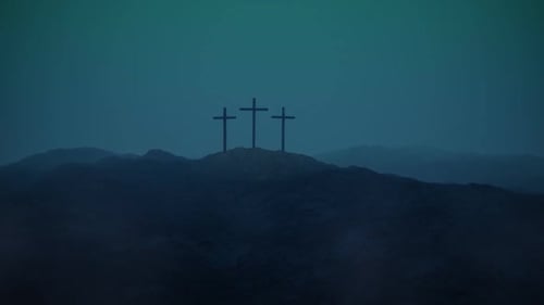 Atmospheric, dark image of three crosses silhouetted on the top of a mountain.