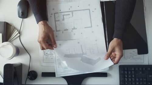 Architect Reviews Floor Plan Blueprints at Desk