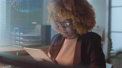 Woman Uses Tablet in Modern Tech Office at Night