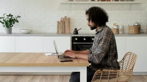 Man Typing on Laptop in Bright Kitchen