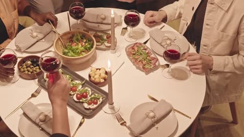 Friends Clinking Wine Glasses at Festive Dinner Table