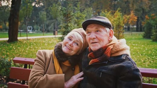 Elderly Couple Enjoying Autumn Together on Park Bench