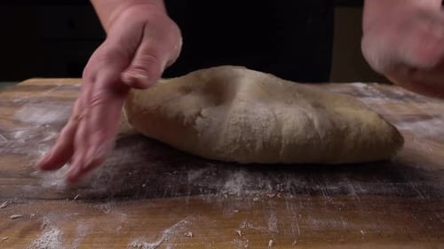 Hands Kneading Pale Dough on Wooden Board