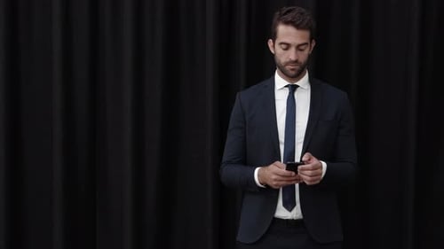 Man in Suit Using Mobile Phone Against Black Background