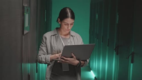 Woman Using Laptop in Dark Data Center