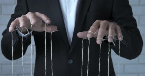 Suited Man Manipulating Puppet Strings in Studio