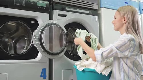 Woman Loading Laundry Into Washing Machine
