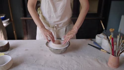 Woman Dipping Ceramic Bowl into Water