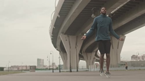Man Skipping Rope Outdoors Under Elevated Roadway