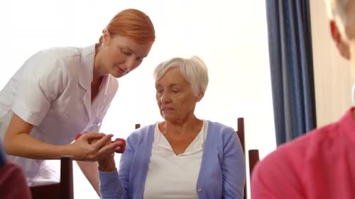 Senior Woman Exercising with Dumbbells Assisted by Healthcare Worker