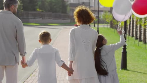 Family Walks Together Holding Colorful Balloons
