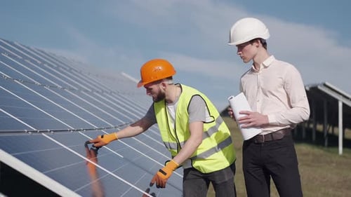 Businessman and Worker Are Checking Solar Batteries Together Outside