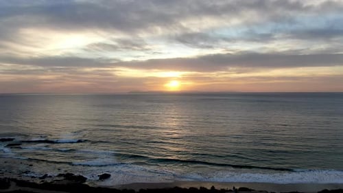 Aerial View of Pacific Ocean Colorful Sunset with Sun Reflection on the Ocean and Deep Clouded Sky