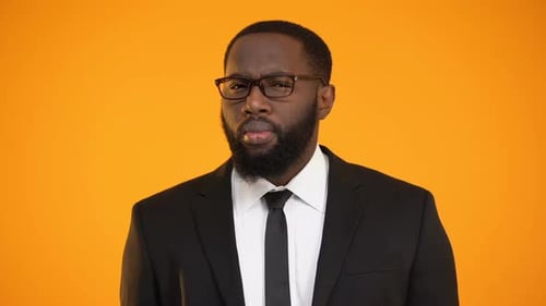 Thoughtful Man in Suit against Orange Background
