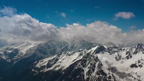 Air Flight Through Mountain Clouds Over Beautiful Snowcapped Peaks of Mountains and Glaciers