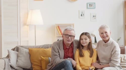 Grandparents Sit with Smiling Grandchild on Couch