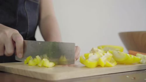 Woman Chopping Yellow Bell Peppers on Board