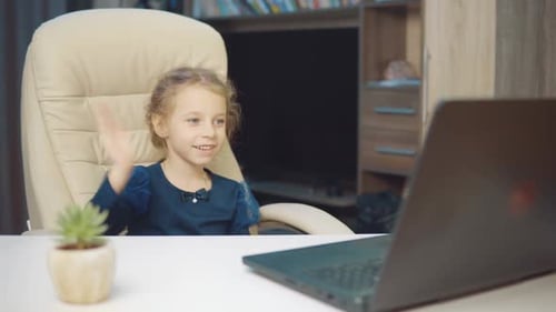 Ein 6-jähriges Mädchen, das eine medizinische Maske trägt, tätigt einen Videoanruf auf einem Laptop.
