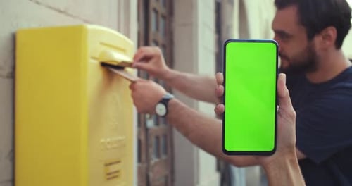 Close Up View of Female Hand Holding Smartphone with Mock Up Screen While Bearded Man Putting Letter