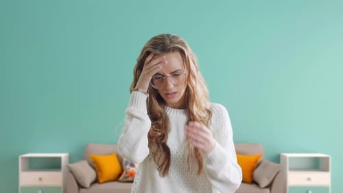 Woman with Headache Rubbing Temples Indoors