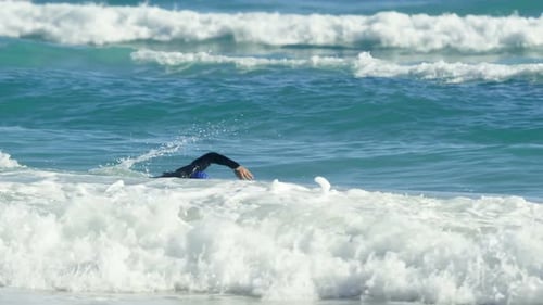 Male surfer swimming in the beach