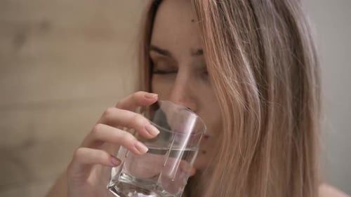 Woman Taking Pill and Drinking Water