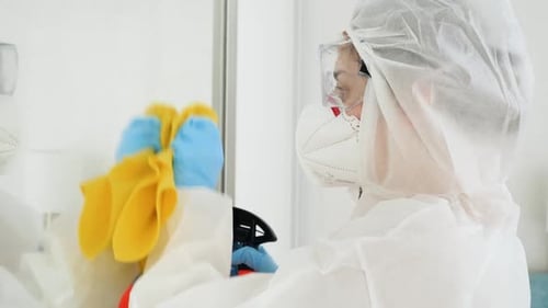 Woman in Hazmat Suit Cleaning Glass Surface