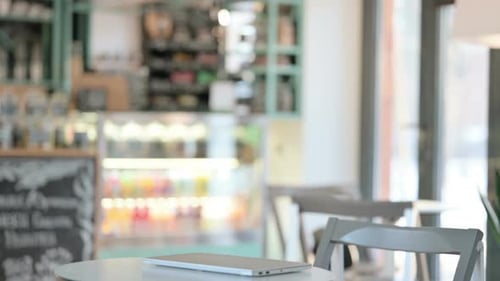 Man Opens Laptop in Bright Cafe