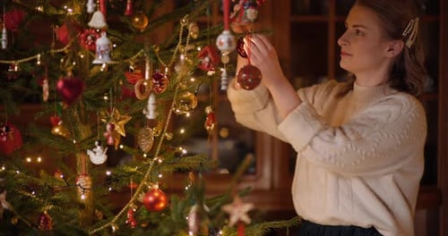 Woman Decorates Beautiful Christmas Tree with Ornaments