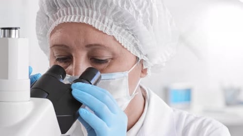 Female Lab Assistant Using Microscope