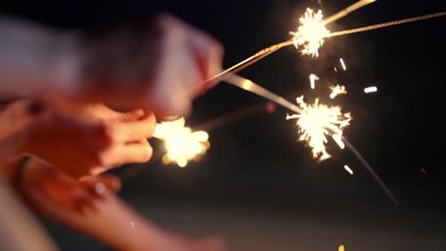 4K Group of Asian woman playing sparklers together on tropical island beach in summer night.