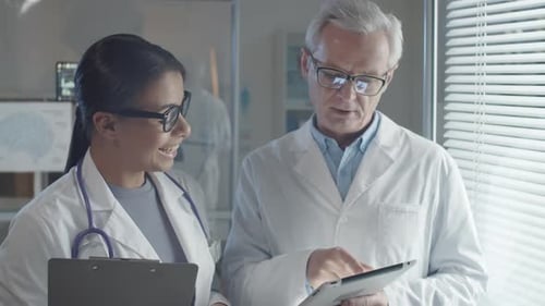 Young Female Doctor Using Tablet and Talking with Male Colleague