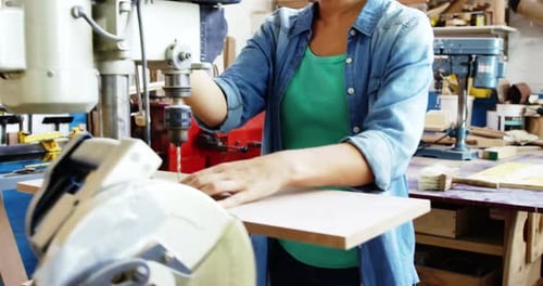 Woman Using Industrial Drill Press in Workshop