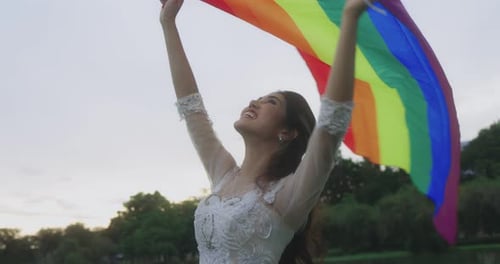Woman Holds Rainbow Flag Up High
