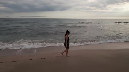 The Girl Walks on the Sand Her Feet are Washed By the Sea