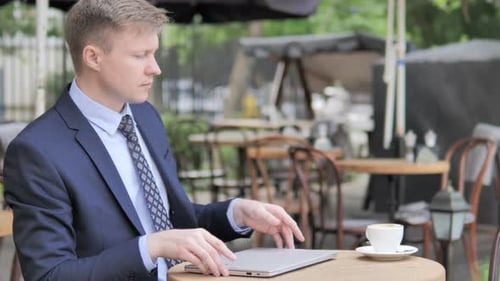 Geschäftsmann verlässt Café-Terrasse nach Schließen des Laptops
