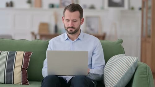 Young Man Working on Laptop on Sofa