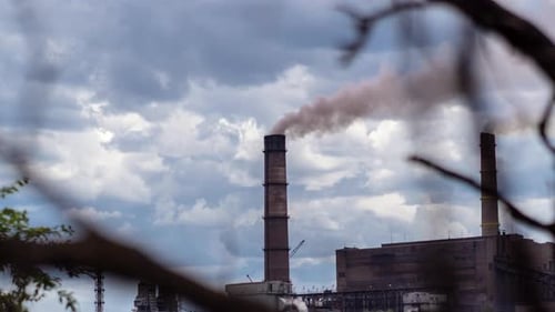 Factory Smokestacks Spewing Smoke Against Cloudy Sky