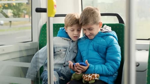 Two Boys Riding Bus and Looking at Phone